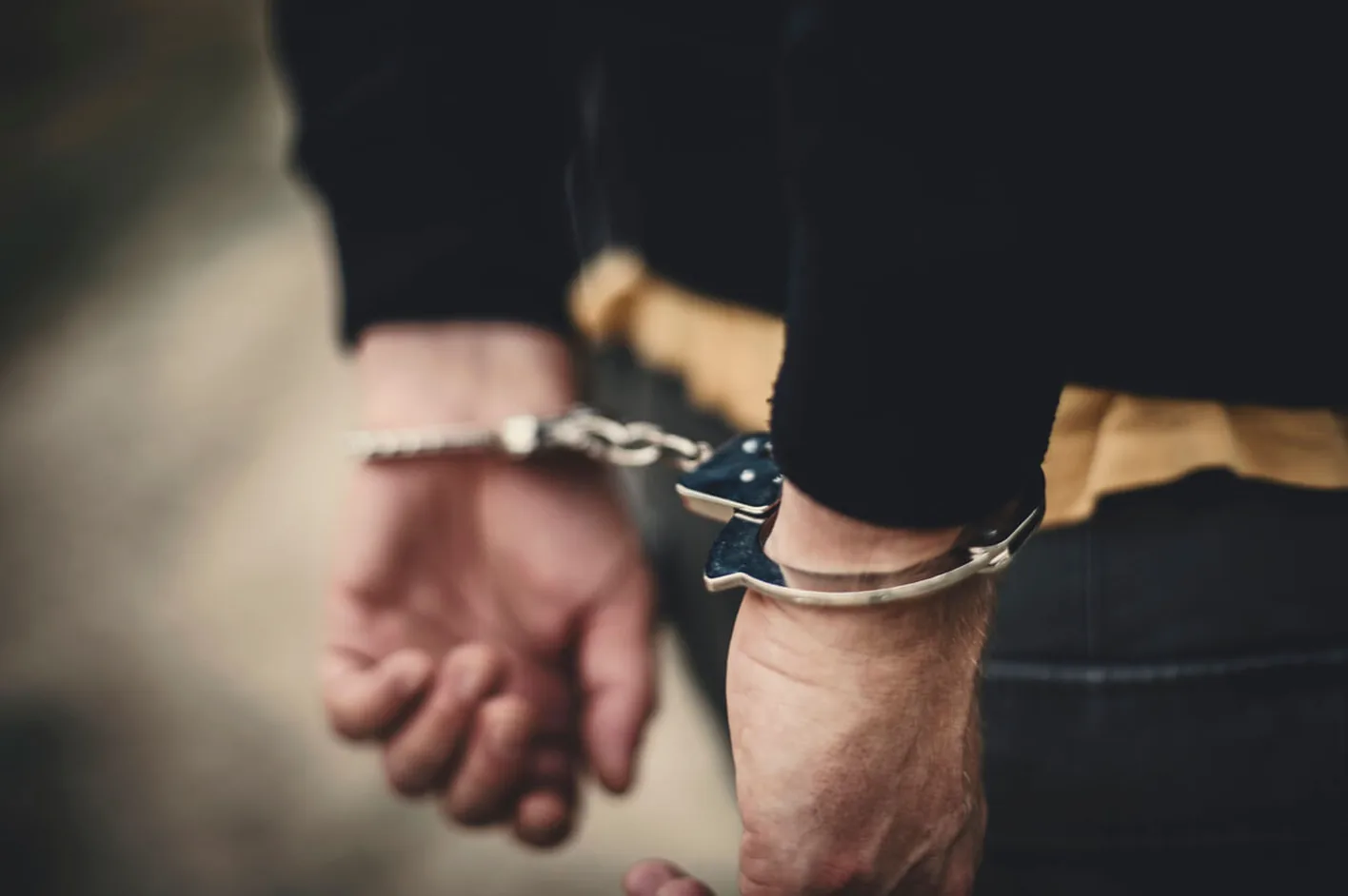 Close-up of hands cuffed behind a person's back