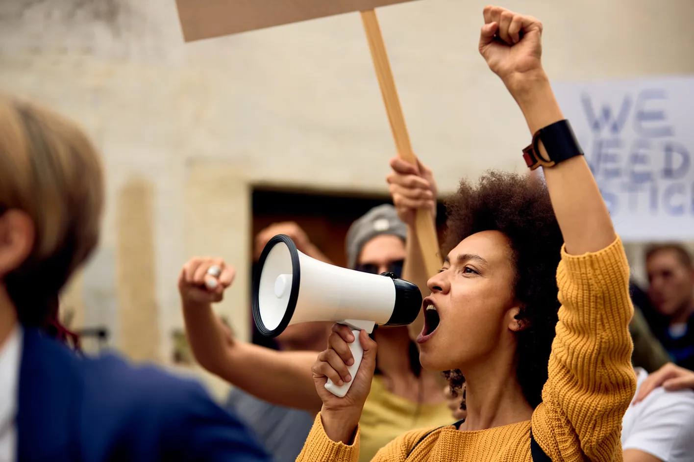 A protester shouting into a megaphone in a crowd holding signs