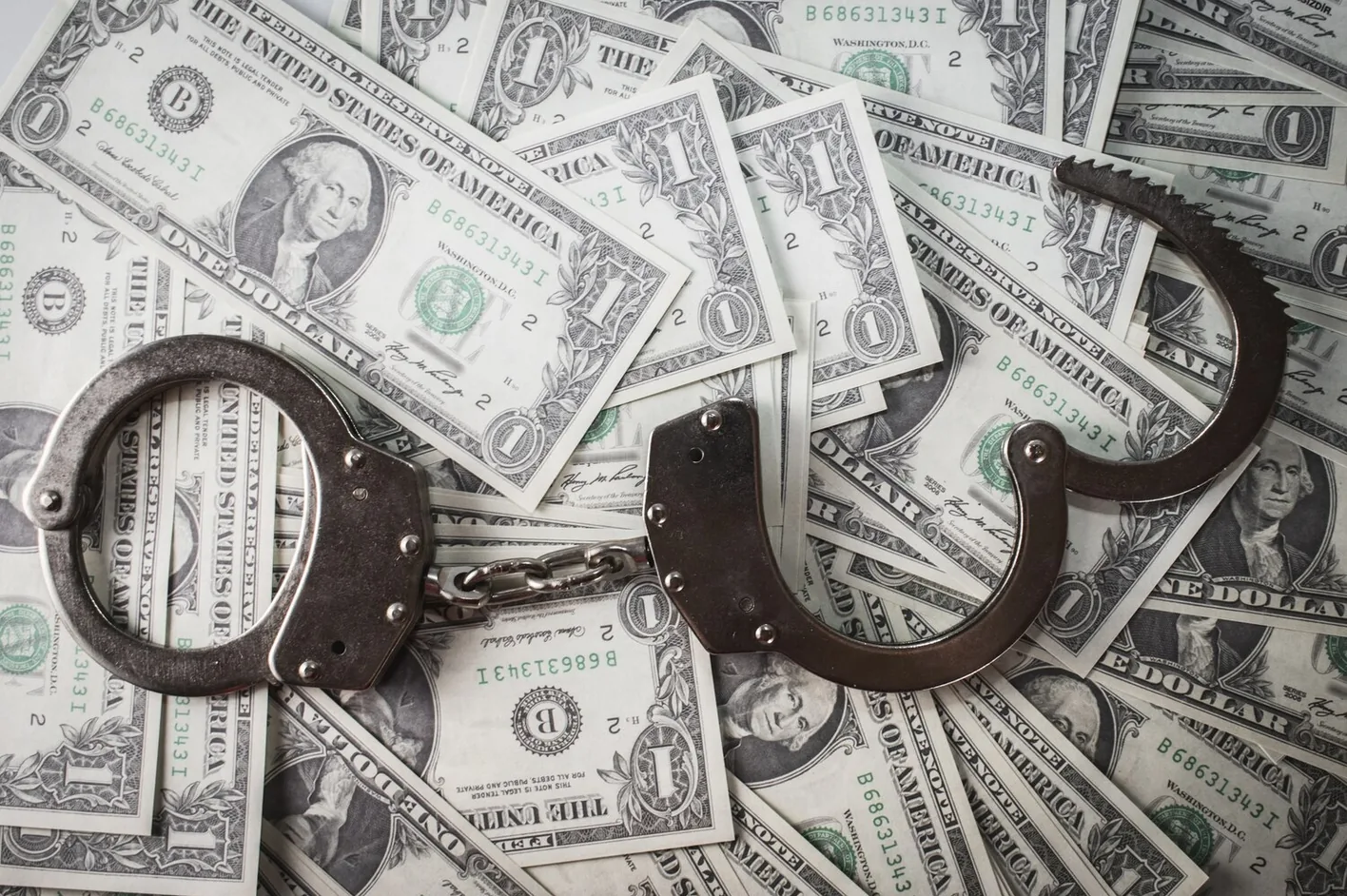 Handcuffs lying on a pile of dollar bills