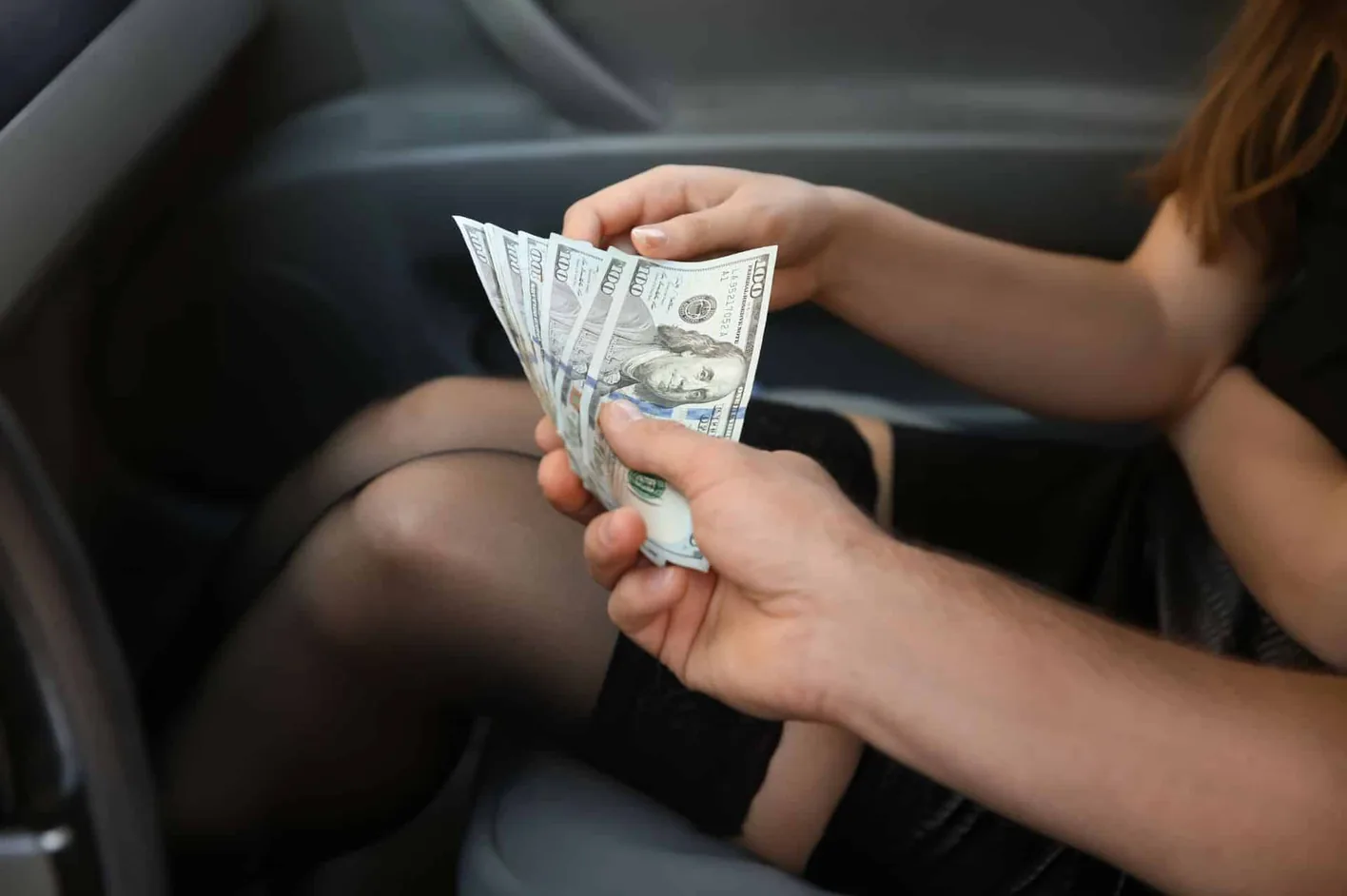 Cash being handed to a woman in a car