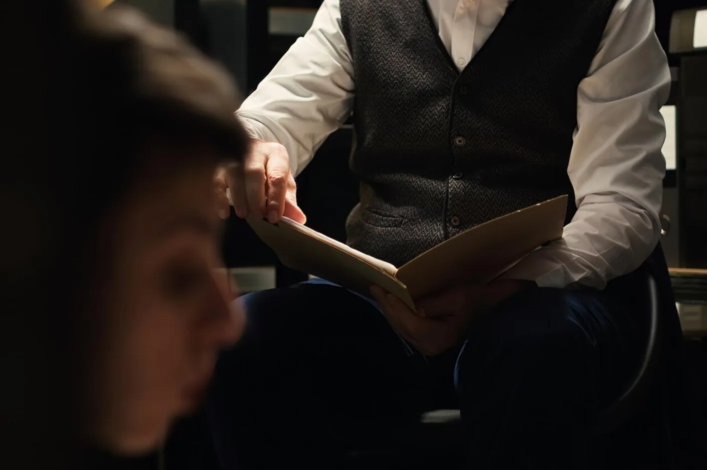 A man reading through a folder of papers as a woman looks on