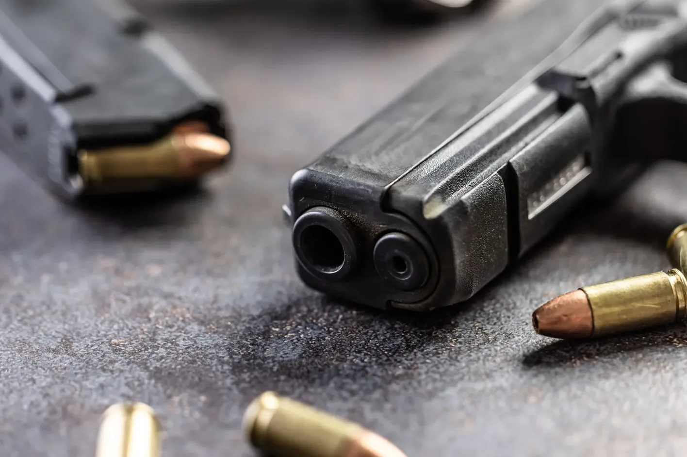 A handgun, a magazine and loose bullets on a table
