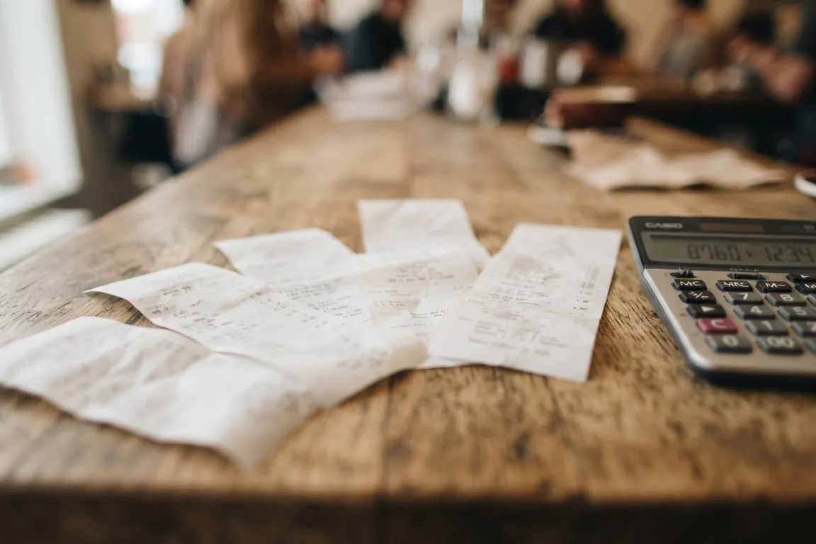 Several small receipts fanned across a countertop beside a calculator, shallow focus
